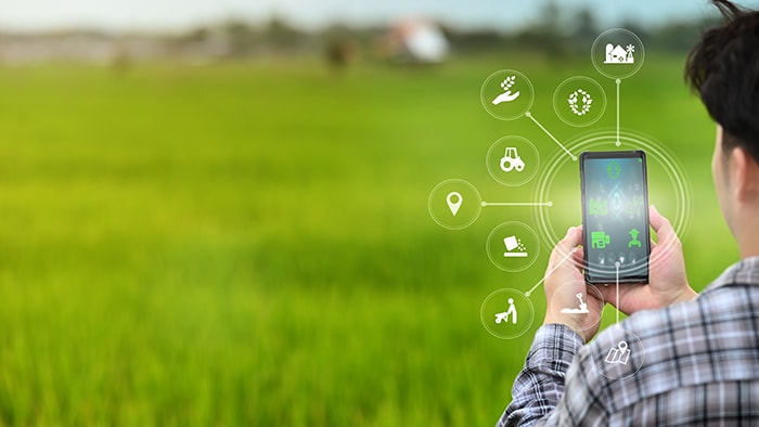 man at farm with a phone connected to various sensors and applications
