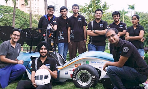 Group photo of IIT Bombay racing team members and their electric car.